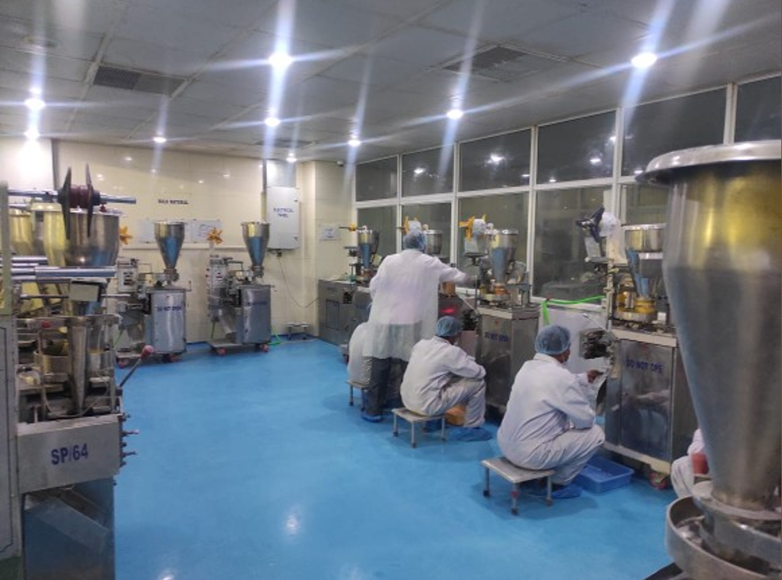 Workers operating packaging machinery on cleanroom floor